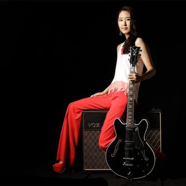 woman sitting on amplifier holding electric guitar